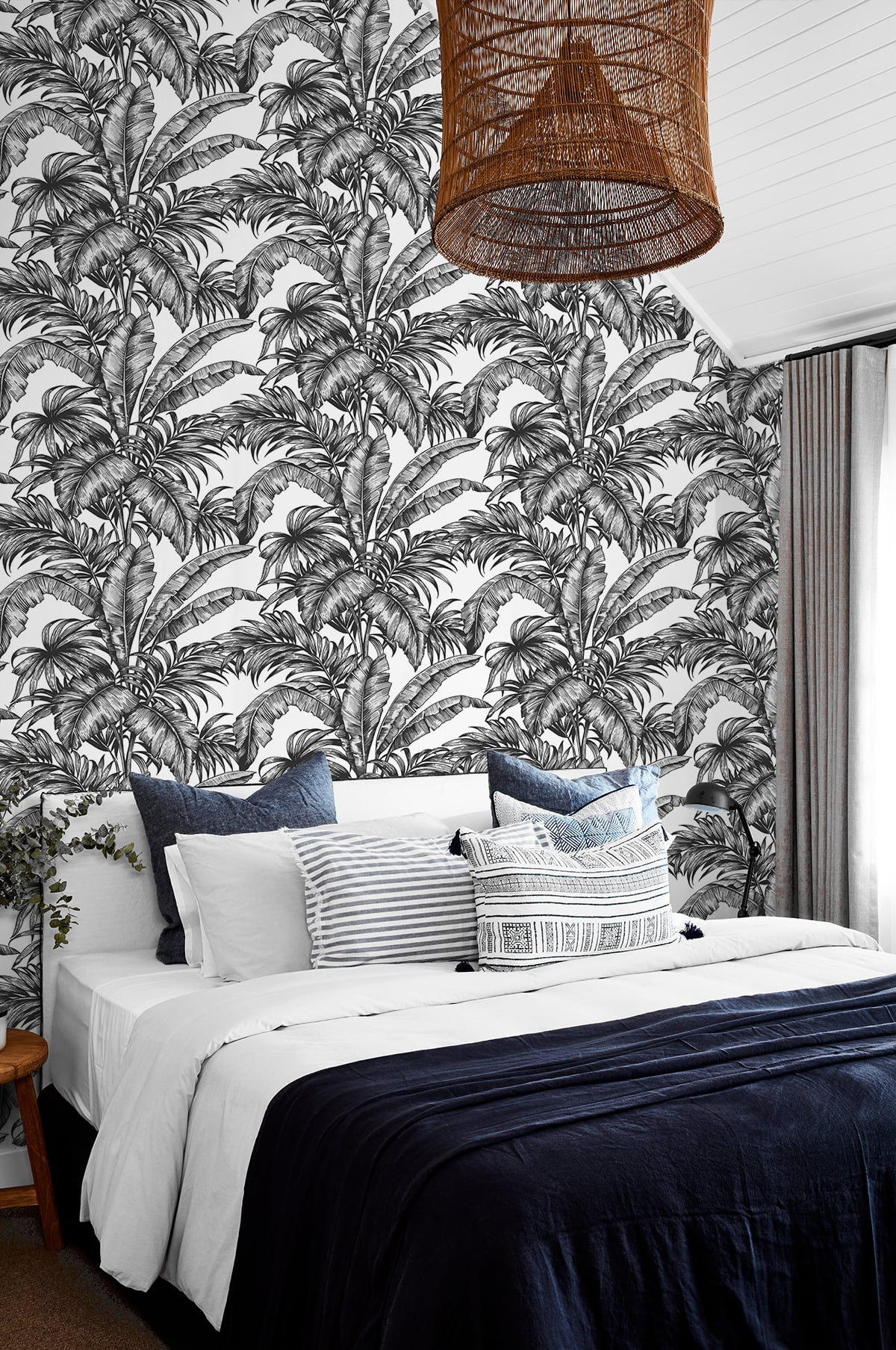Bedroom with a wall decorated with Black Rainforest Palm Peel & Stick Casa Mia Wallcovering and a wicker lampshade.