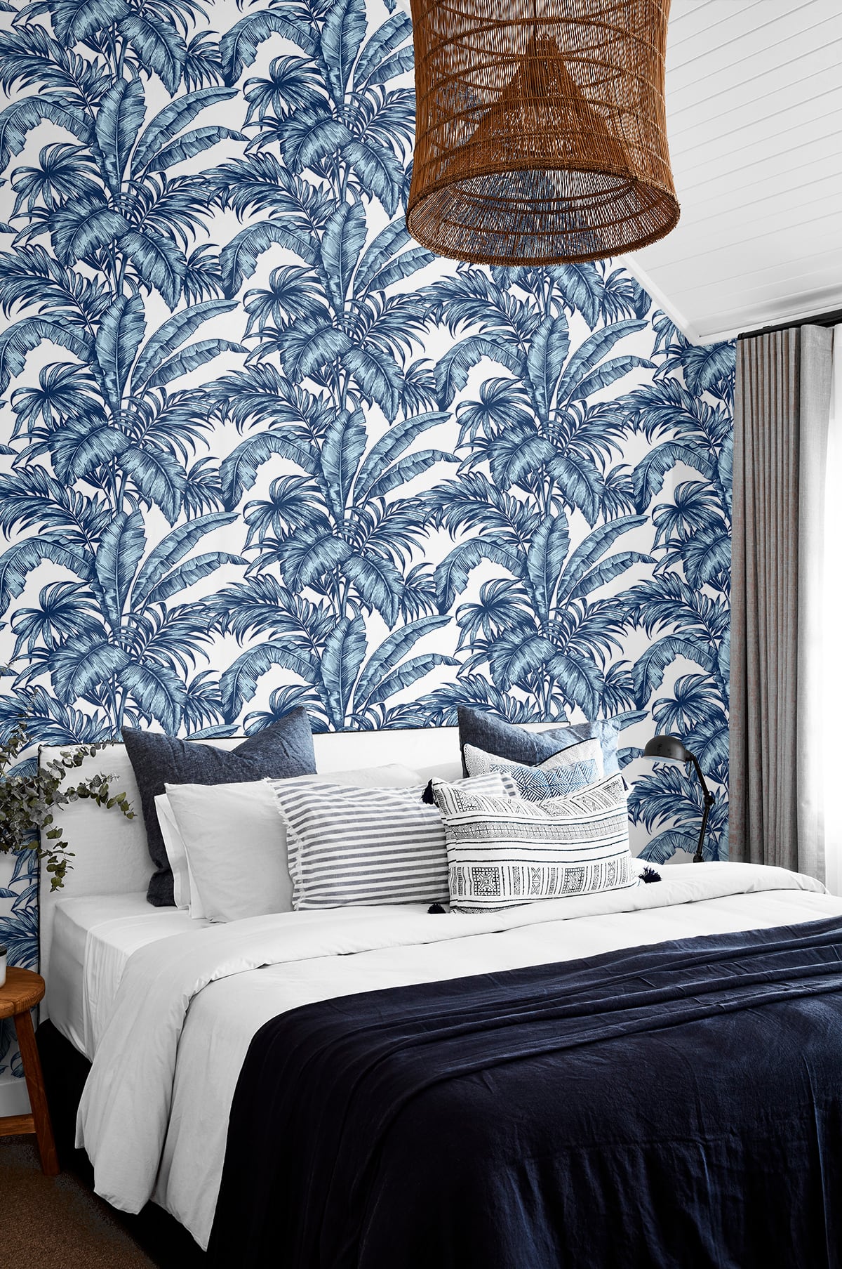 Bedroom with a wall decorated with Blue Rainforest Palm Peel & Stick Casa Mia Wallcovering and a wicker lamp.