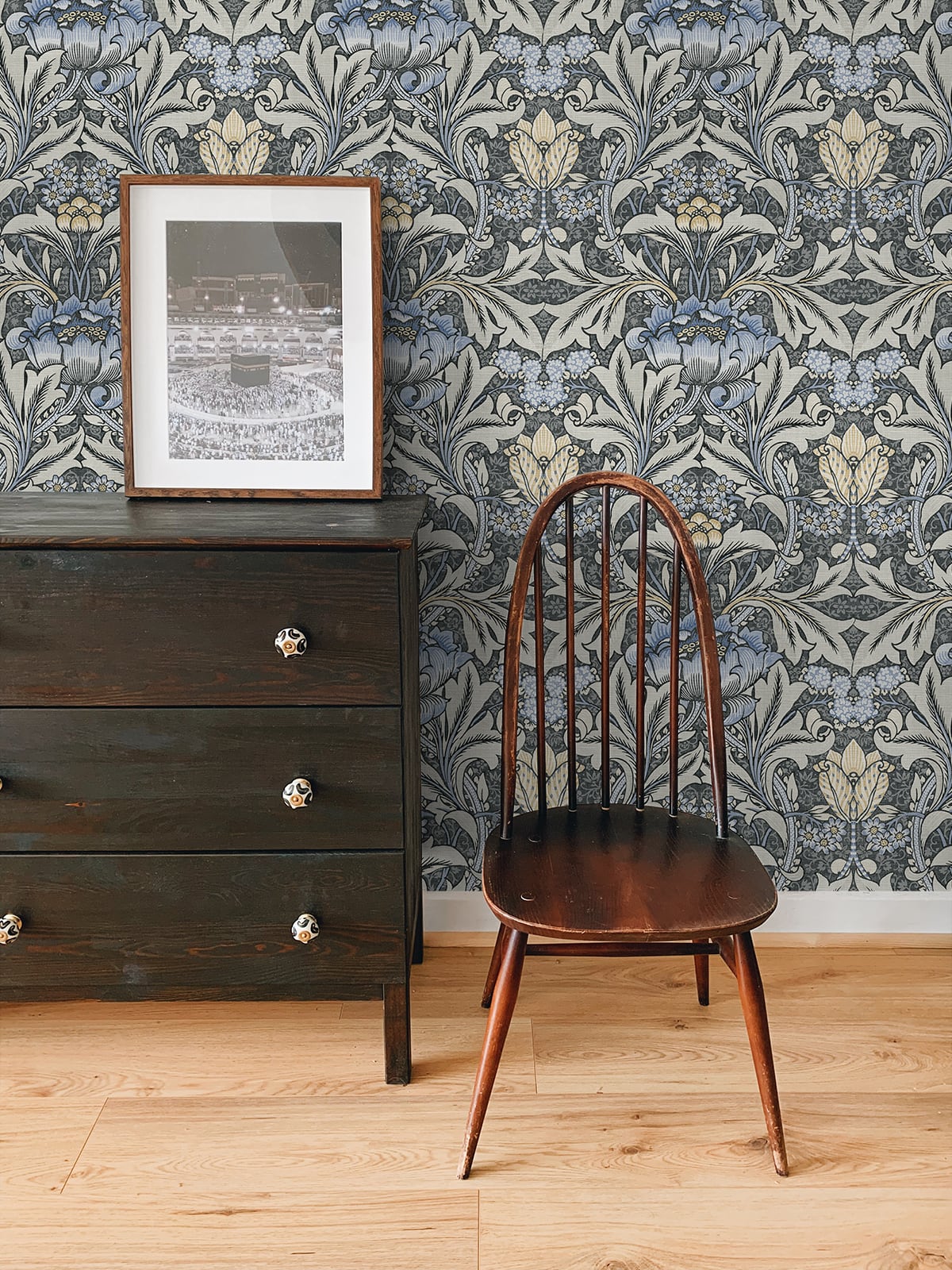 Wooden chair and dresser against a wall decorated with Black & Blue Bear's Breeches Peel & Stick Casa Mia Wallcovering.