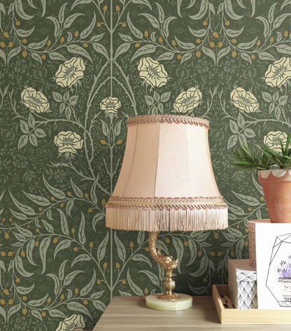 Decorative lamp with a beige shade on a wooden surface against a wall decorated with Green Drawn Floral Peel & Stick Casa Mia Wallcovering.