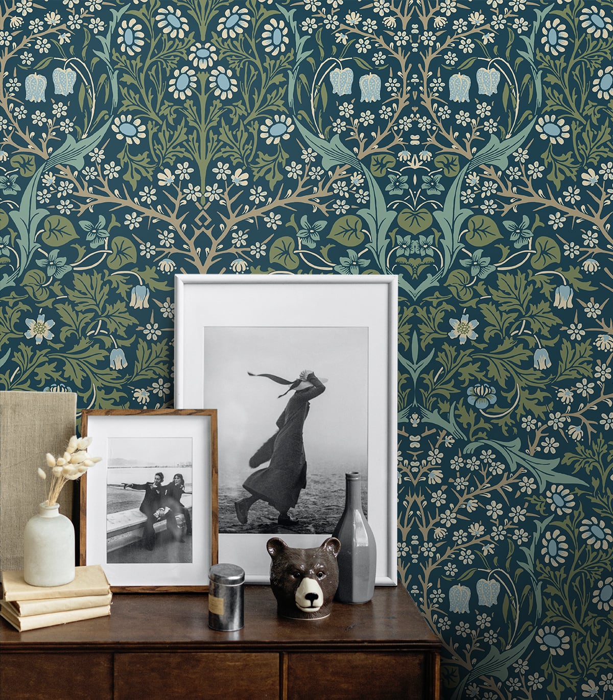 Decorative wall with Blue & Green Victorian Floral Peel & Stick Casa Mia Wallcovering, framed pictures, and a bear figurine on a wooden surface.