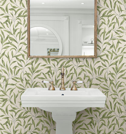 Bathroom with wall decorated Green Leafy Branches Peel & Stick Casa Mia Wallcovering patterned wallpaper, white sink, and gold-framed mirror.