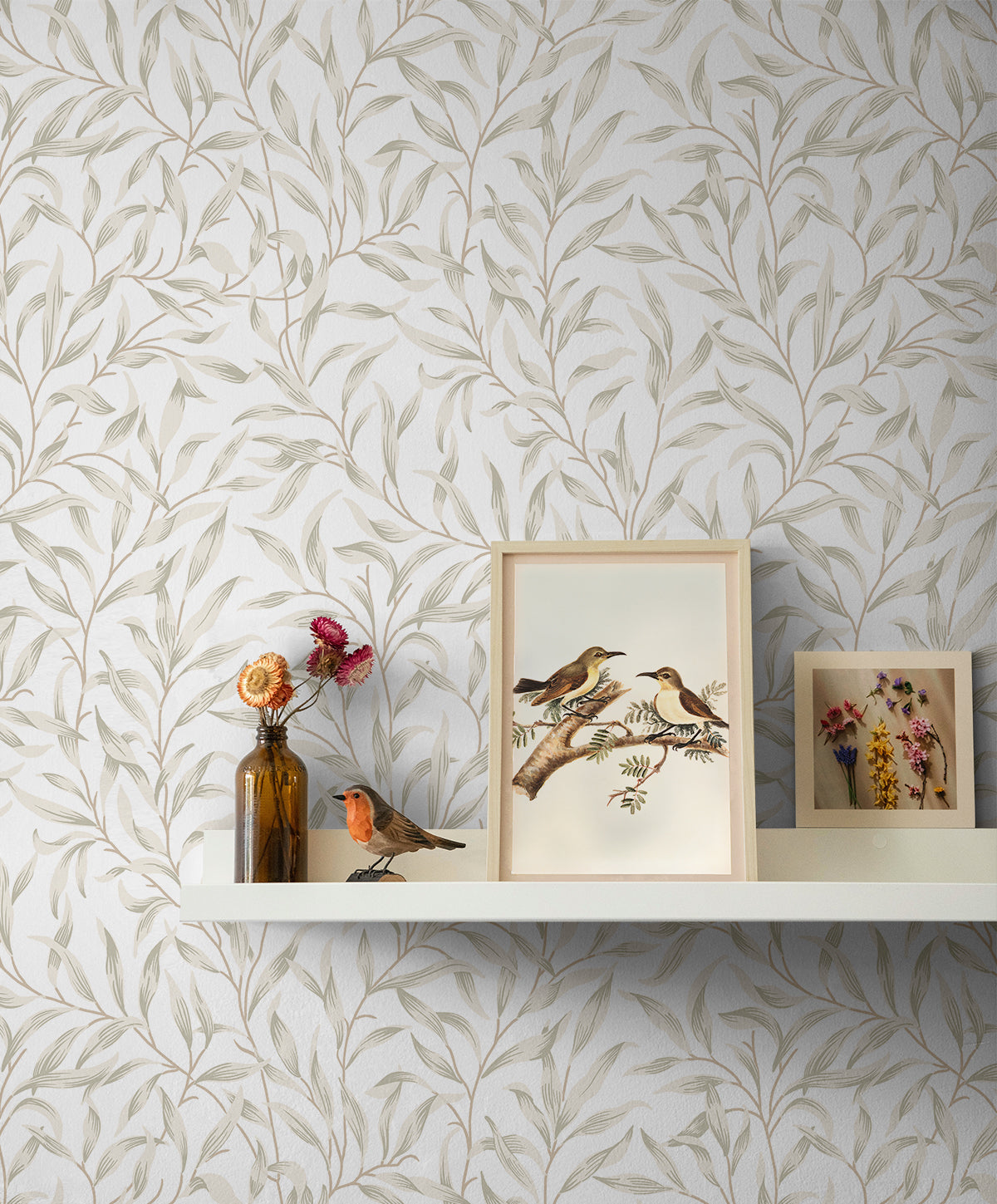 Shelf with framed artwork against a wall decorated with Beige Leafy Branches Peel & Stick Casa Mia Wallcovering.