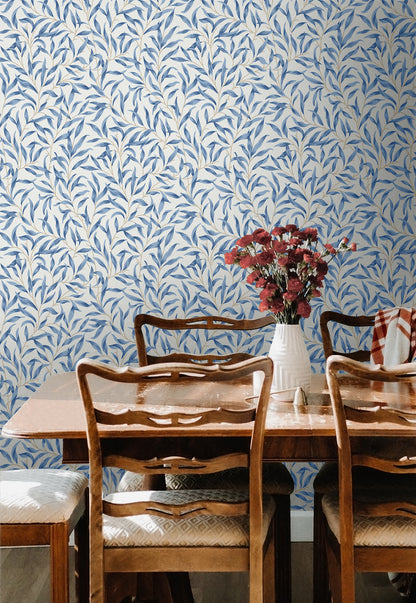 Dining room with wooden table and chairs against a wall decorated with Blue Leafy Branches Peel & Stick Casa Mia Wallcovering.