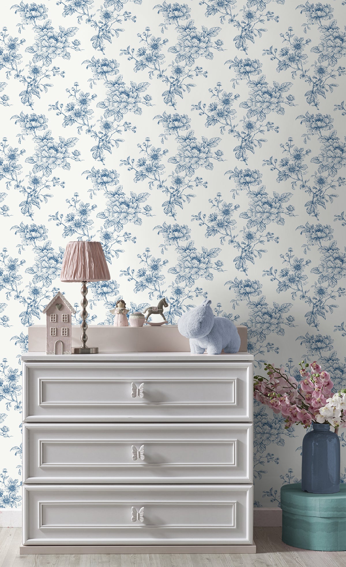 White dresser with decorative items against a wall decorated with Blue Cherished Rose Peel & Stick Casa Mia Wallcovering.