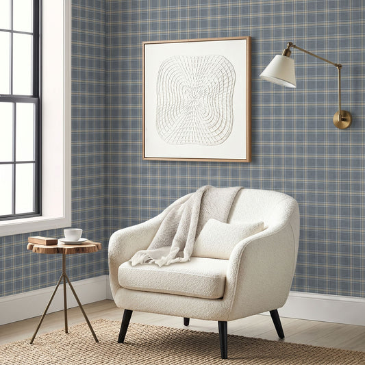 Cozy armchair with blanket, small round table, wall art, sconce, and Tartan Wallpaper in a country-style room.