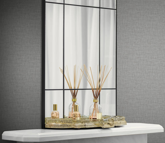 A gold tray with reed diffusers and spray bottle sits before a large mirror and Linen Texture Commercial Vinyl wallpaper.