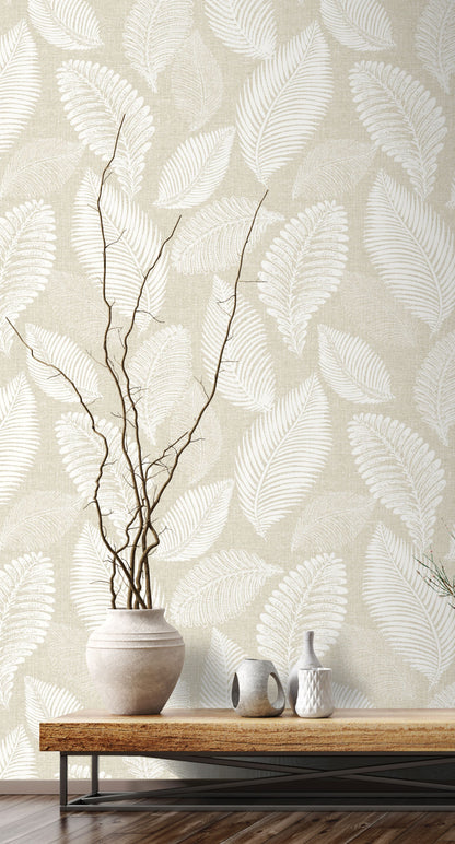 Wall decorated with Sand Cream Scattered Leaves Wallpaper, vase with branches, and small bottles on a wooden table.