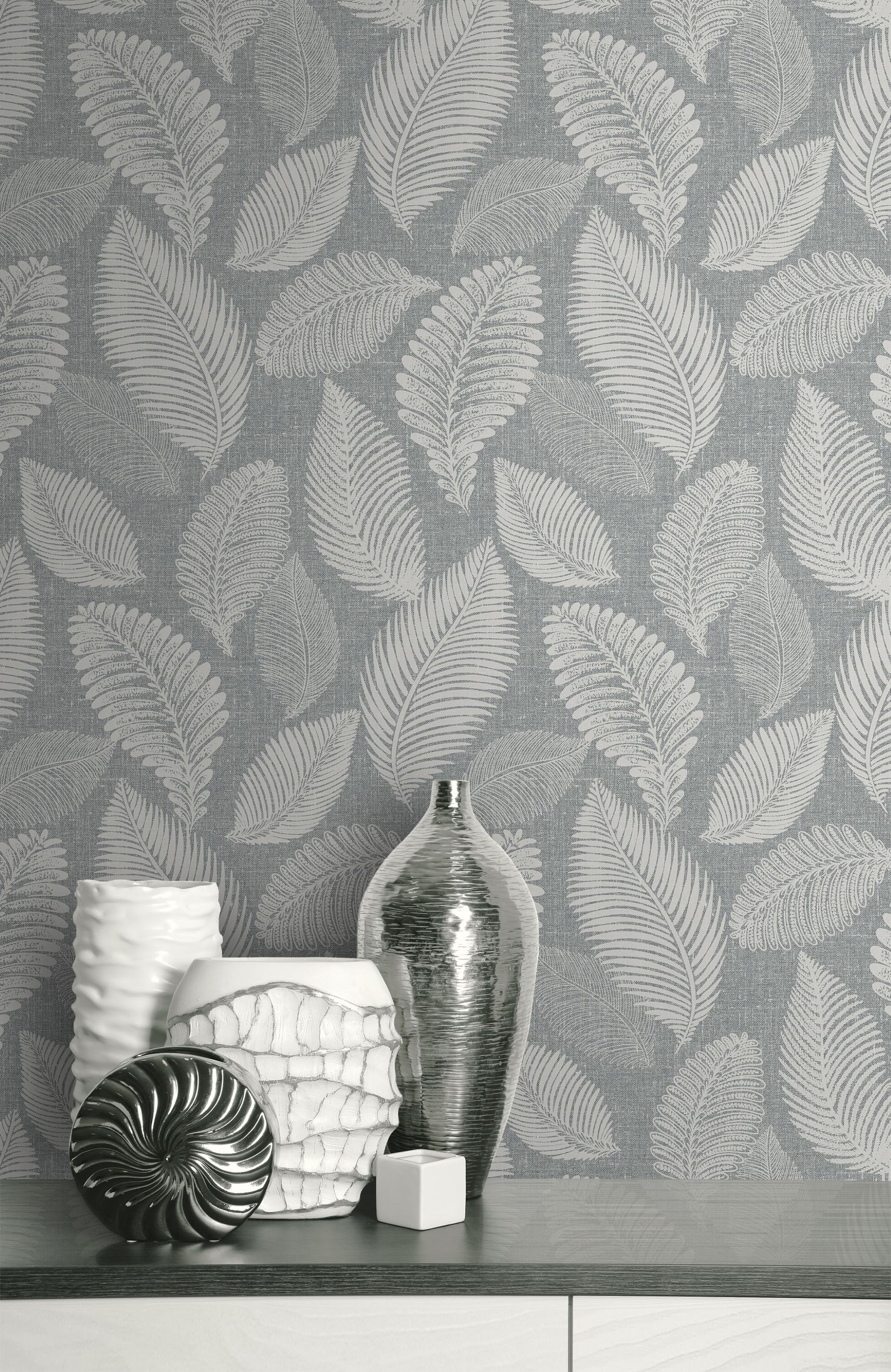 Decorative vases and a bottle on a surface with a wall decorated with Templeton Gray Scattered Leaves Wallpaper.
