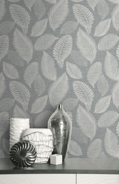 Decorative vases and a bottle on a surface with a wall decorated with Templeton Gray Scattered Leaves Wallpaper.
