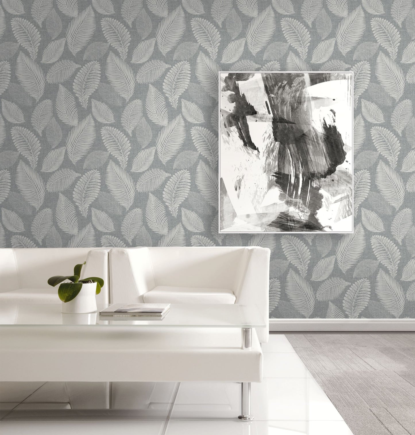 Living room with white sofa, abstract art, and wall decorated with Templeton Gray Scattered Leaves Wallpaper.
