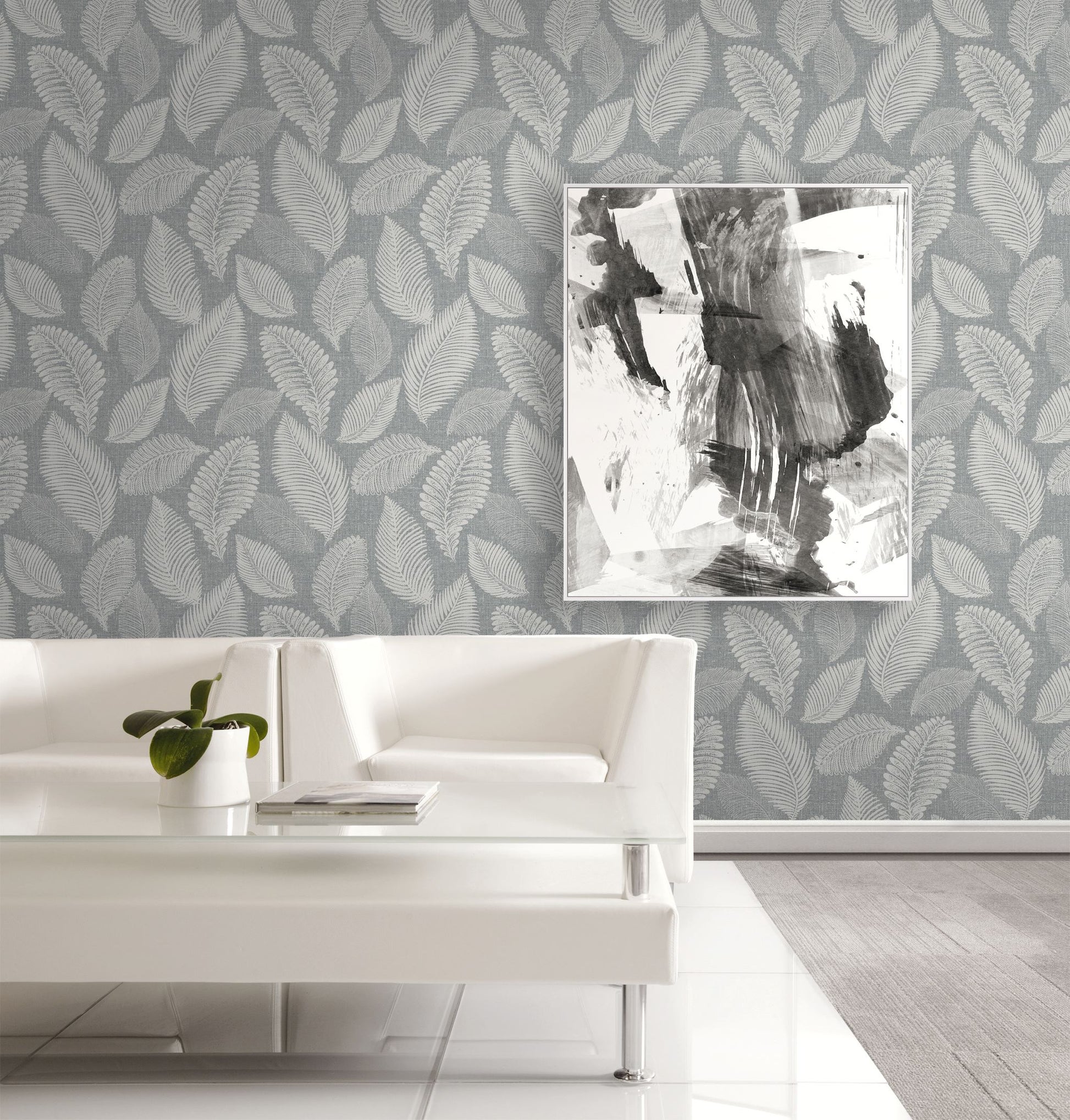 Living room with white sofa, abstract art, and wall decorated with Templeton Gray Scattered Leaves Wallpaper.
