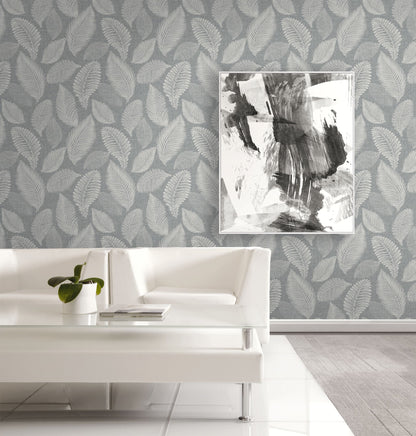 Living room with white sofa, abstract art, and wall decorated with Templeton Gray Scattered Leaves Wallpaper.
