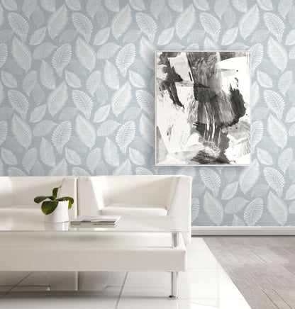 Living room with white sofa, abstract art, and a wall decorated with Light Blue Scattered Leaves Wallpaper.
