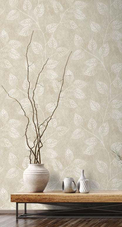 Wall decorated with Sand Yellow & Cream Branch Of Leaves Wallpaper, vase with branches, and small ceramic items on a wooden table.