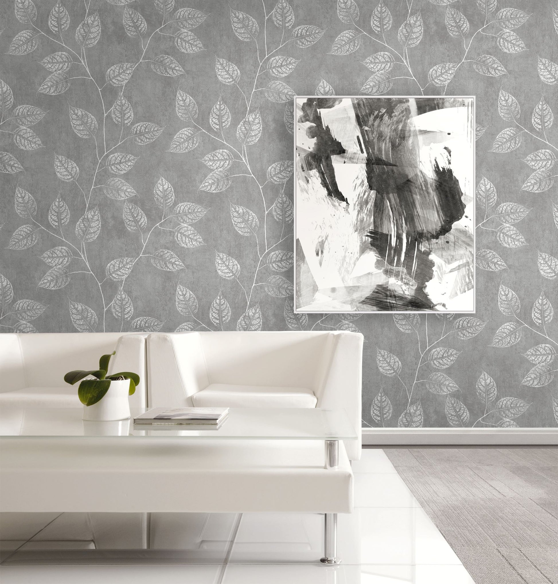 Living room with white sofa, abstract painting, and wall decorated with Mist Gray Branch Of Leaves Wallpaper.

