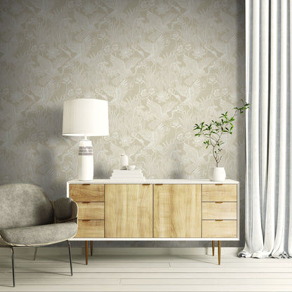 Modern living room with wooden sideboard, gray armchair, and decorative items against a wall decorated with Beige Marsh Heron Wallpaper.
