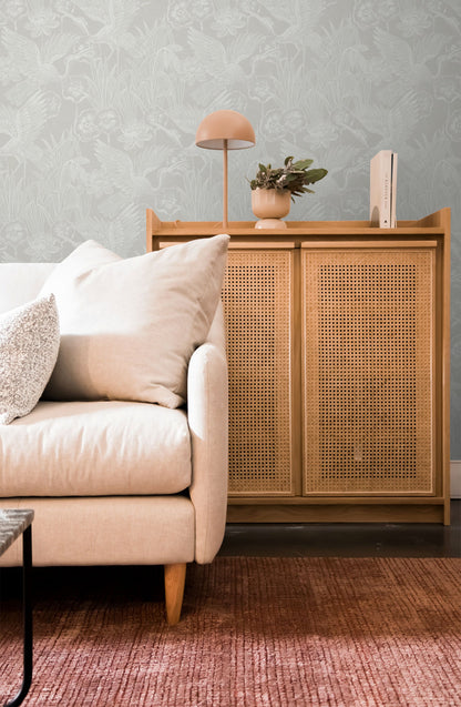 Living room with beige sofa, wooden cabinet, and decorative items against a wall decorated with White/Off White Marsh Heron Wallpaper.
