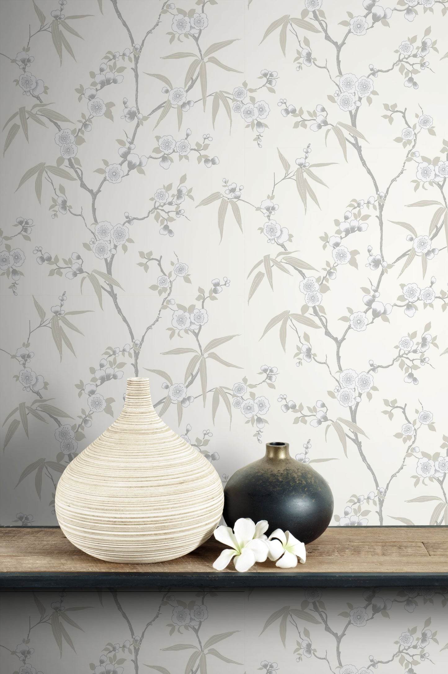 Two vases on a wooden surface with wall decorated with White/Off White Blossom Spring Flower Wallpaper.
