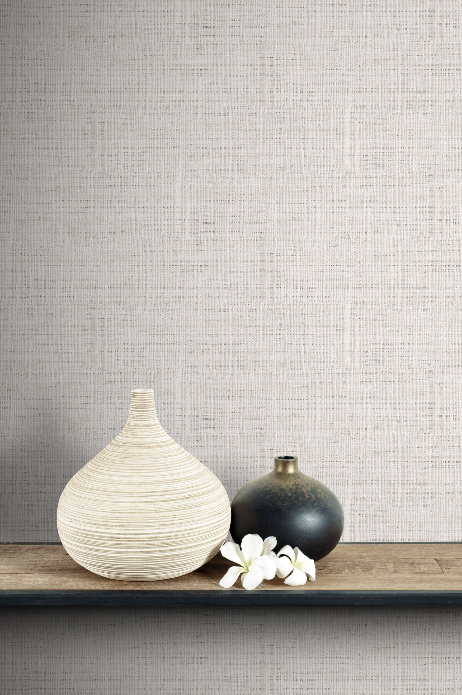 Two vases and a small white flower arrangement on a wooden surface with a wall decorated with Pebble Linen Fabric Commercial & Vinyl.
