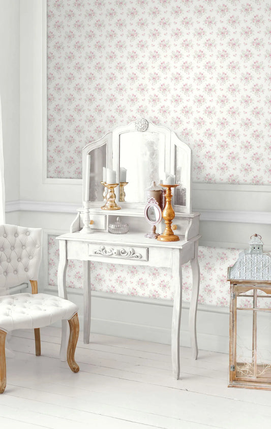 White vintage vanity with mirror, candles, and brush next to tufted chair, set against Cottage Bouquet Wallpaper.