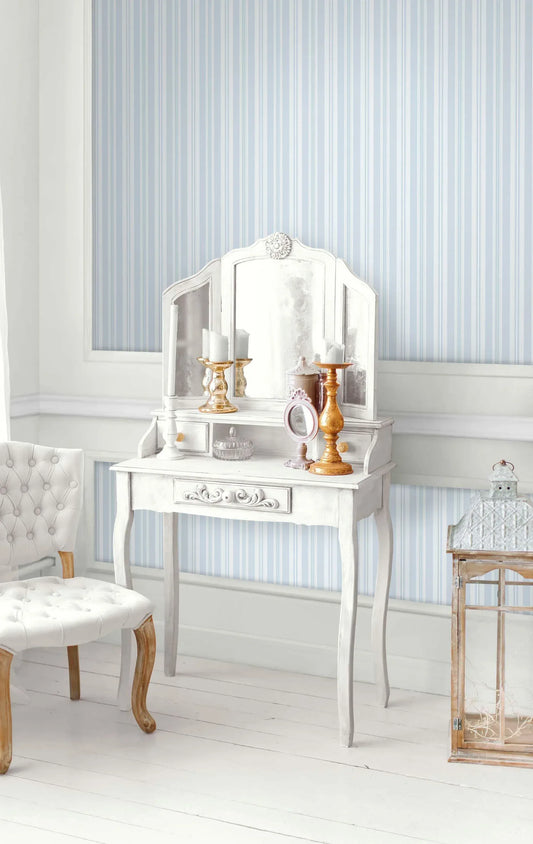 White vintage vanity, decor, and tufted chair set against Pretty Stripe Wallpaper in a bright room.