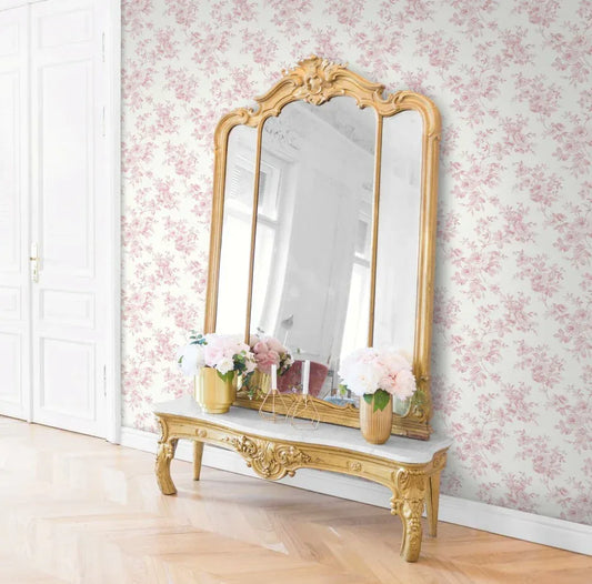 A gold mirror, marble table, and flower vases add cottage charm to the room's Blooming Roses Wallpaper.