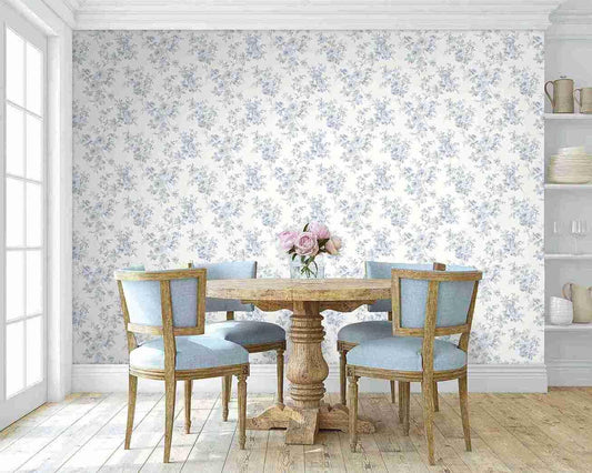 A round wooden table with blue chairs pops against Blooming Roses Wallpaper, adding cottage charm to the dining room.