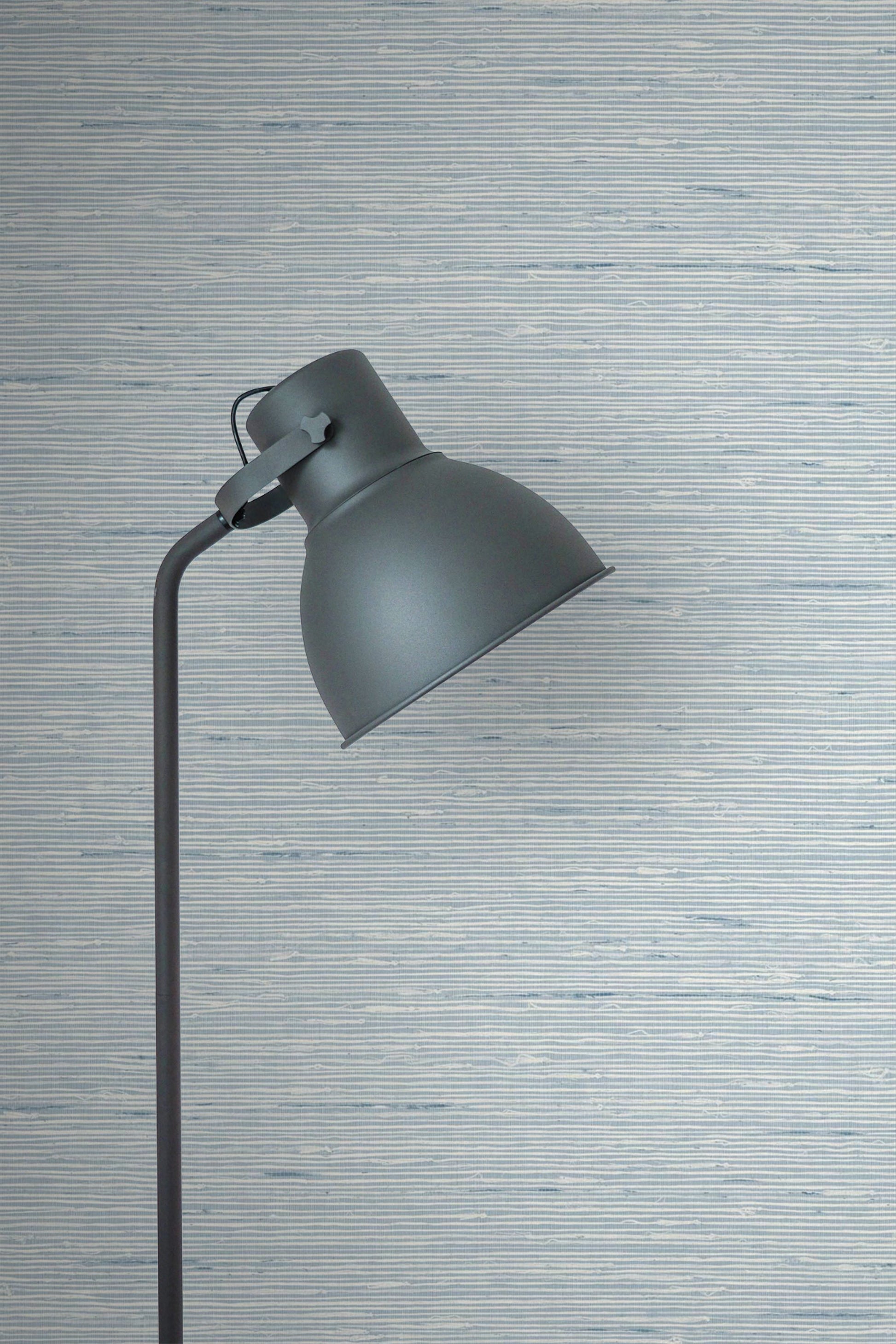 Dark gray floor lamp against a wall decorated with Light Blue Natural Weave Commercial & Vinyl.

