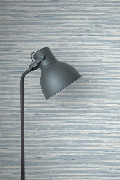 Dark gray floor lamp against a wall decorated with Light Blue Natural Weave Commercial & Vinyl.
