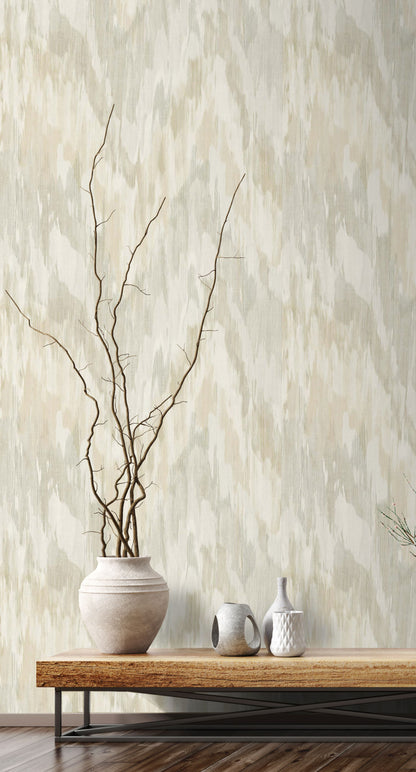 Vase with branches on a wooden table against a wall decorated with Beige & Green Watercolor Wave Wallpaper.
