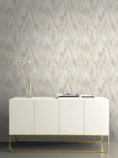 White sideboard with gold legs against a wall decorated with Beige & Gray Watercolor Wave Wallpaper.

