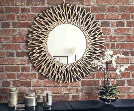 Gold sunburst mirror on Brick Peel Stick wallpaper, above a black table with vases.
