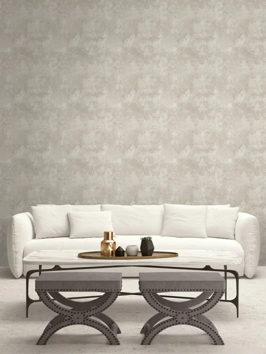 A white sofa, neutral pillows, and gray ottomans enhance the Lys Flower Wallpaper in this minimalist living room.