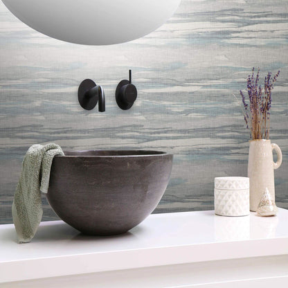 Bathroom sink with decorative elements against a textured Gray & Green Grasscloth Waves Wallpaper.