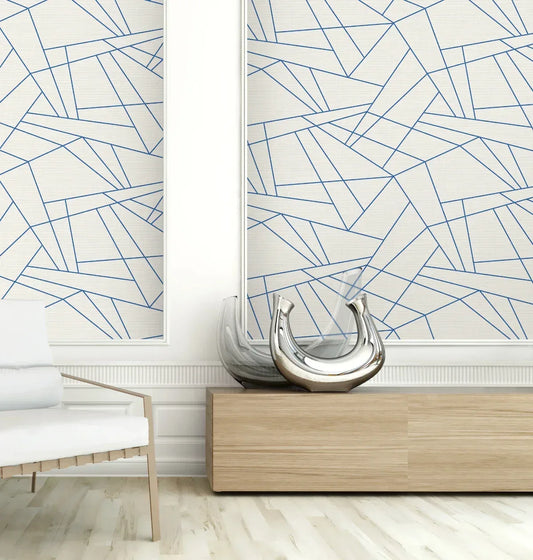 Modern room featuring Geo Triangles Wallpaper in blue and white, a wood cabinet, glass vases, and a cushioned chair.